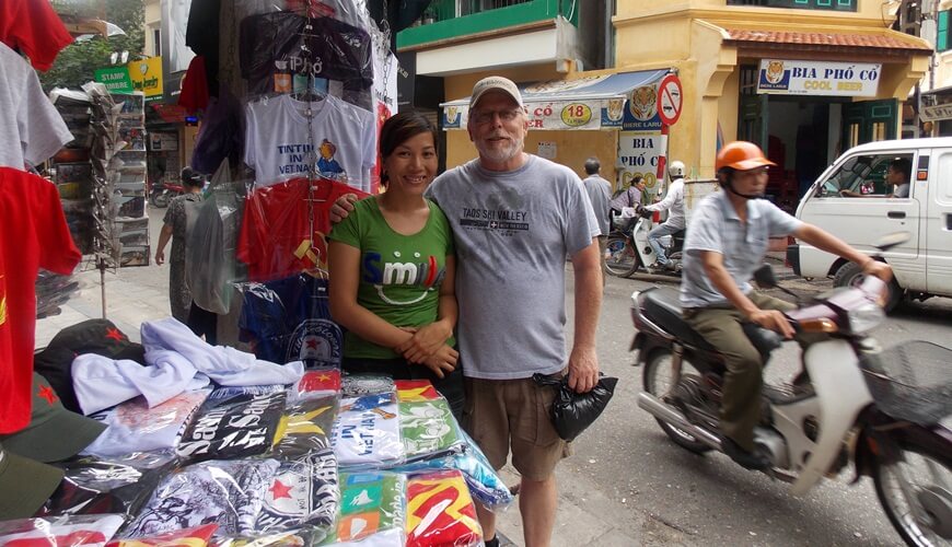 Tourist taking photos with friendly T-Shirt seller in Hanoi Old Quarter