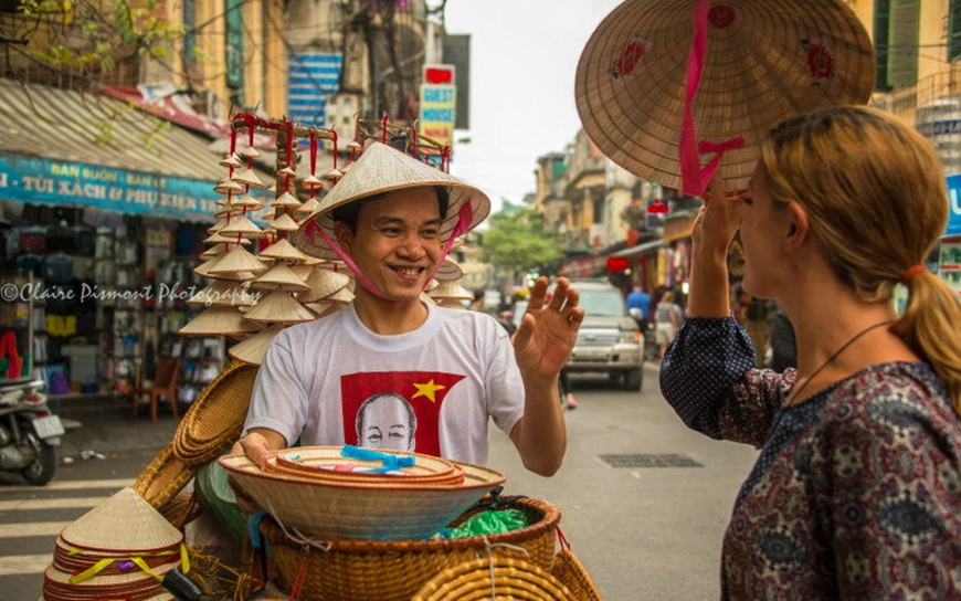 Tourist buying Non La from a smiley street vendor in Hanoi (Photo by Claire Pismont)